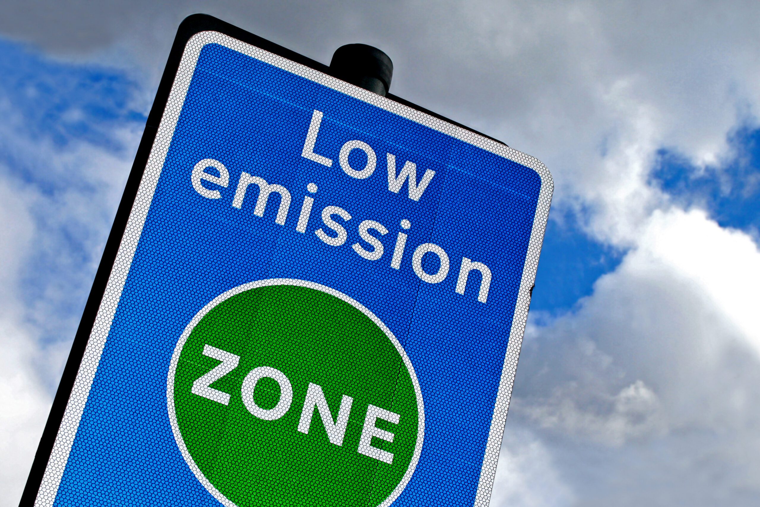A low emission zone sign with a blue, cloudy sky in the background