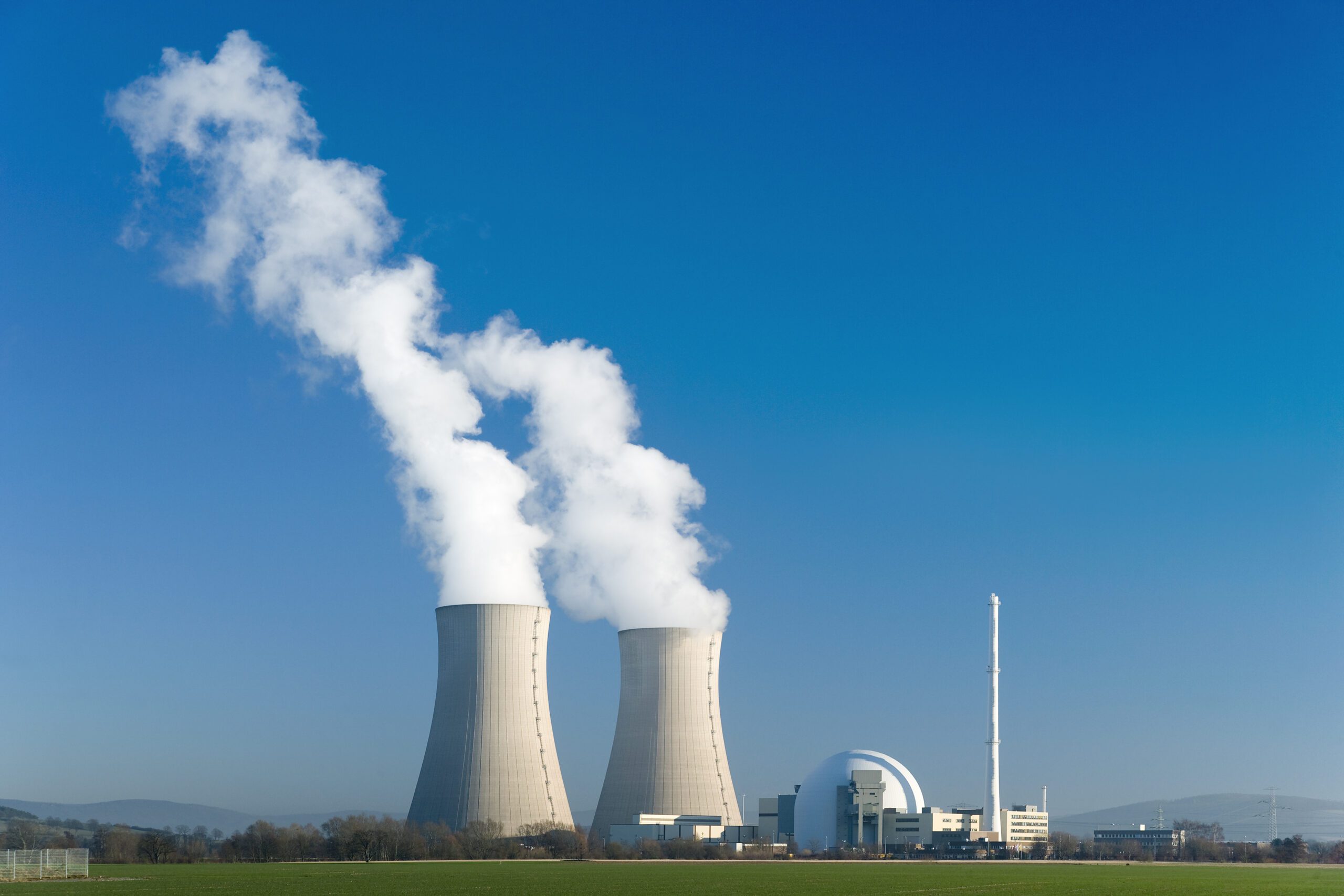 A power plant with two cooling towers releasing vapour clouds.